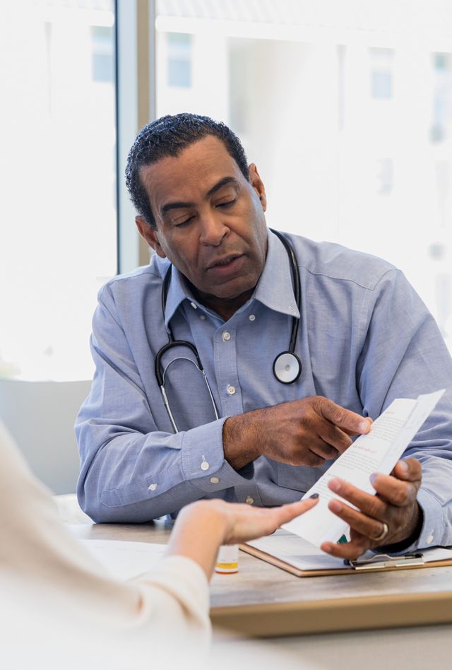 Male doctor points to the paper in his hand as he speaks to a female patient.
