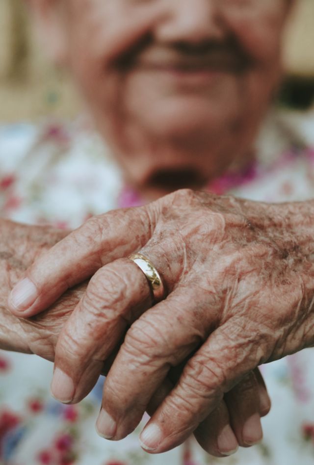 A person with wrinkled hands sits