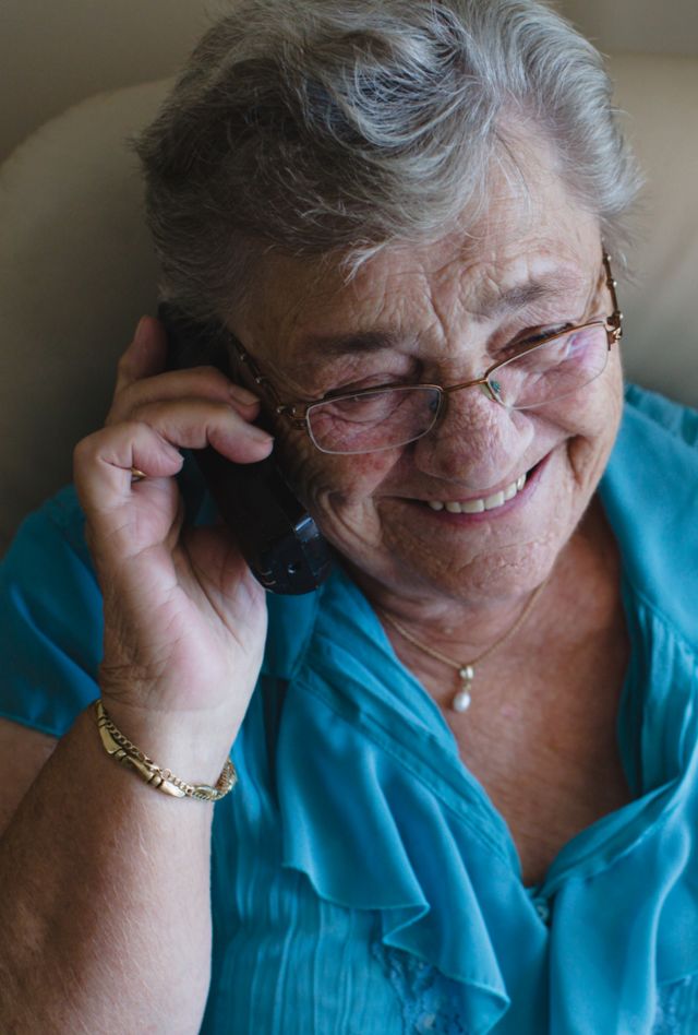 A woman smiles while holding a phone to her ear