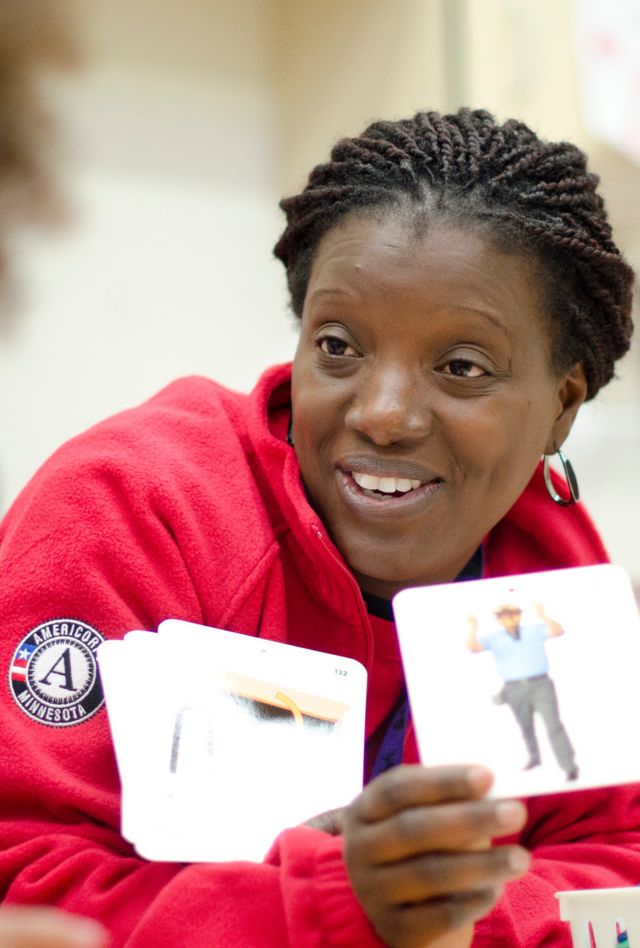 A teacher holds up cards with images for a child in a classroom