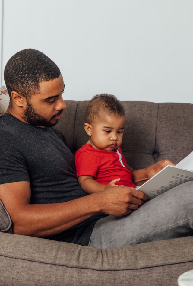 Father reading to his son on the couch.