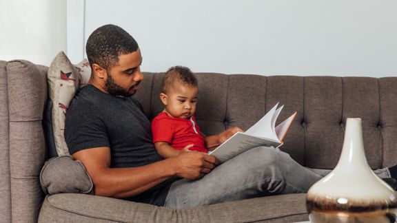 Father reading to his son on the couch.