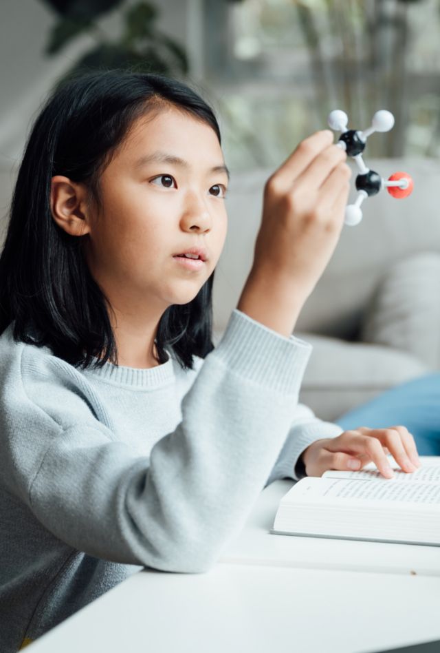 Elementary science student using plastic atom model educational toy