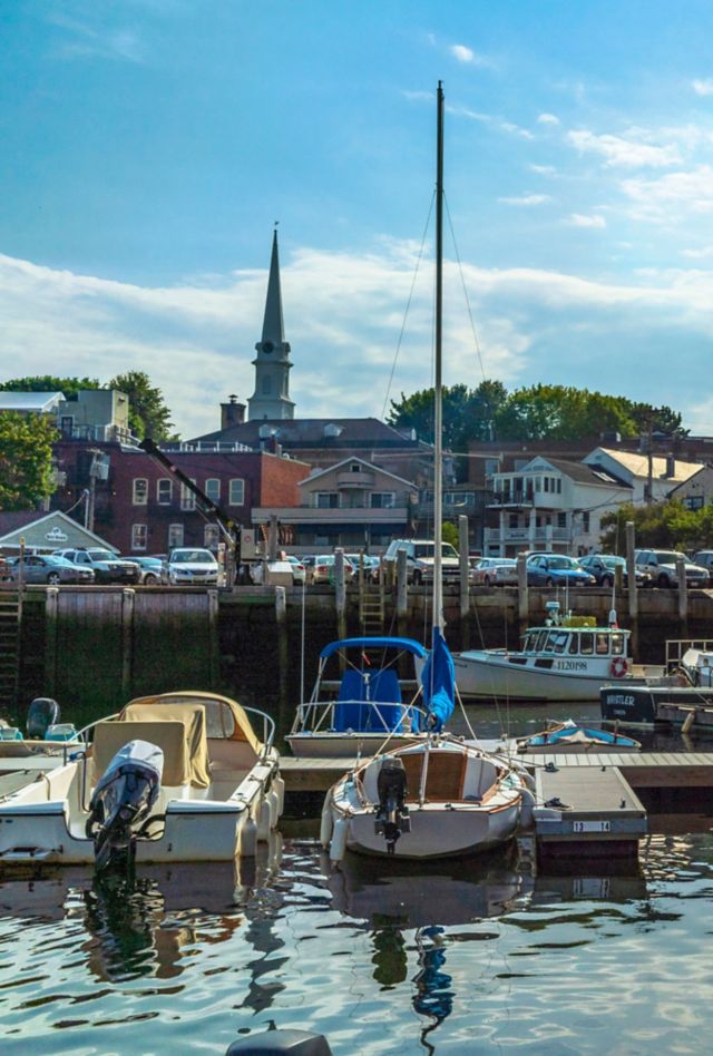 Small boats are docked at a harbor in front of buildings