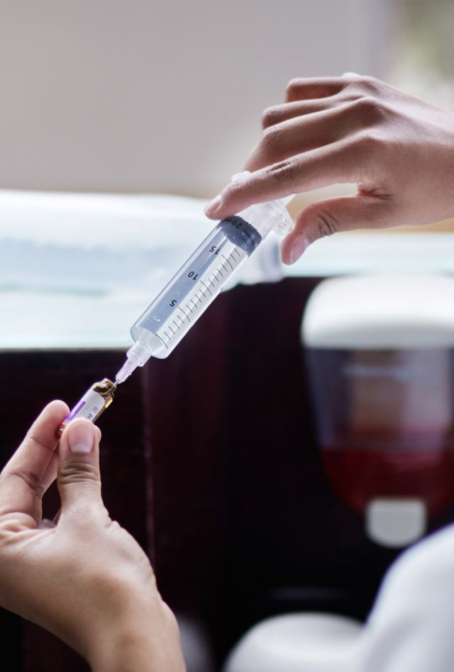 A healthcare worker fills a syringe in a clinic