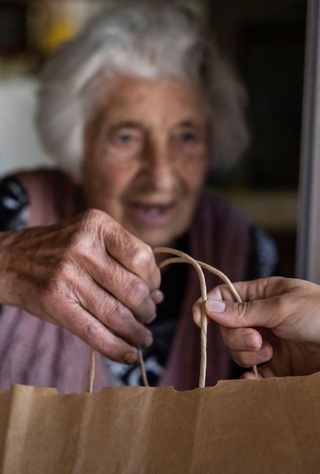 Elderly woman receiving food delivery at the doorway.