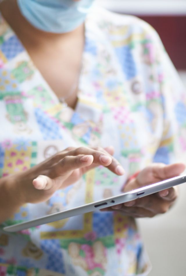 healthcare hospital concept: Doctor's use of medical healthcare technology at work. Medical pediatrician doctor with face mask is holding an ipad tablet in a hospital