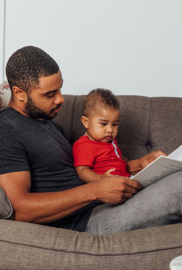 Father reading to his son on the couch.