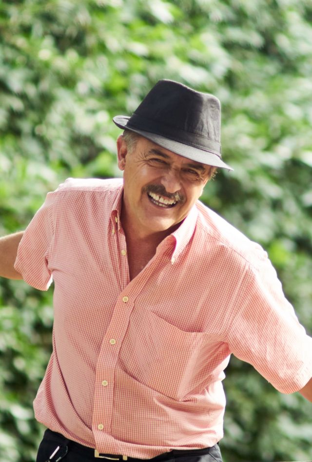 Happy senior grandparent with grandchild playing in the park. Happy people across generations, kid and senior grandparent. Mature senior man has hat and pink shirt