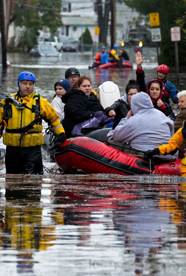 People, some waving to those on dry ground, are rescued by boat 