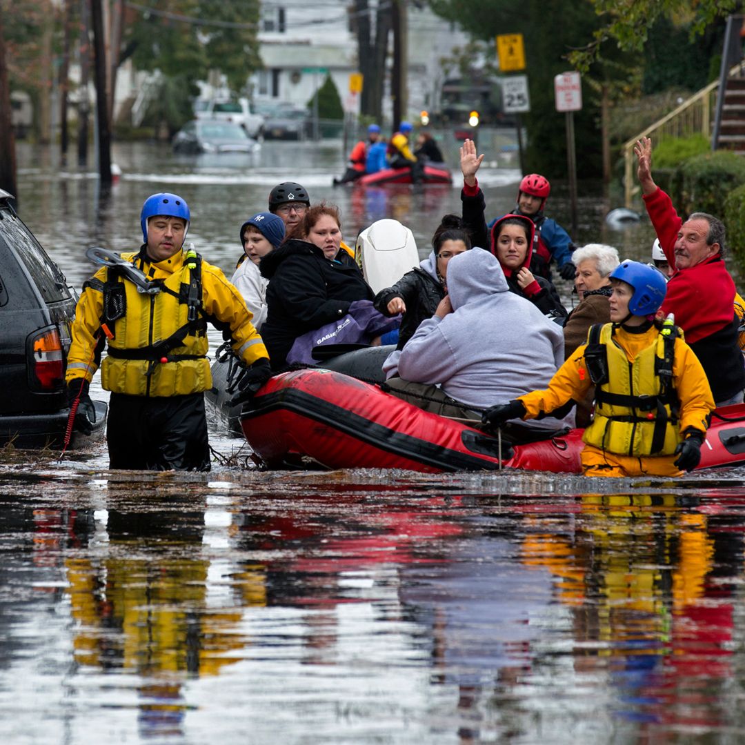 People, some waving to those on dry ground, are rescued by boat in Little Ferry, N.J. Tuesday, Oct. 30, 2012 in the wake of superstorm Sandy. The storm, which made landfall Monday evening, caused multiple fatalities, halted mass transit and cut power to more than 6 million homes and businesses.