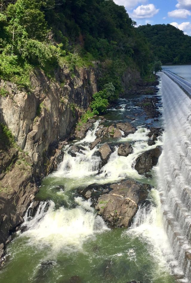Water runs down a concrete dam into a river