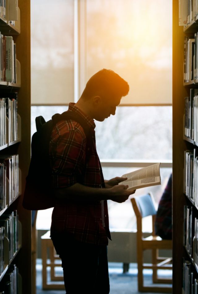Male student in the book stacks at a library.