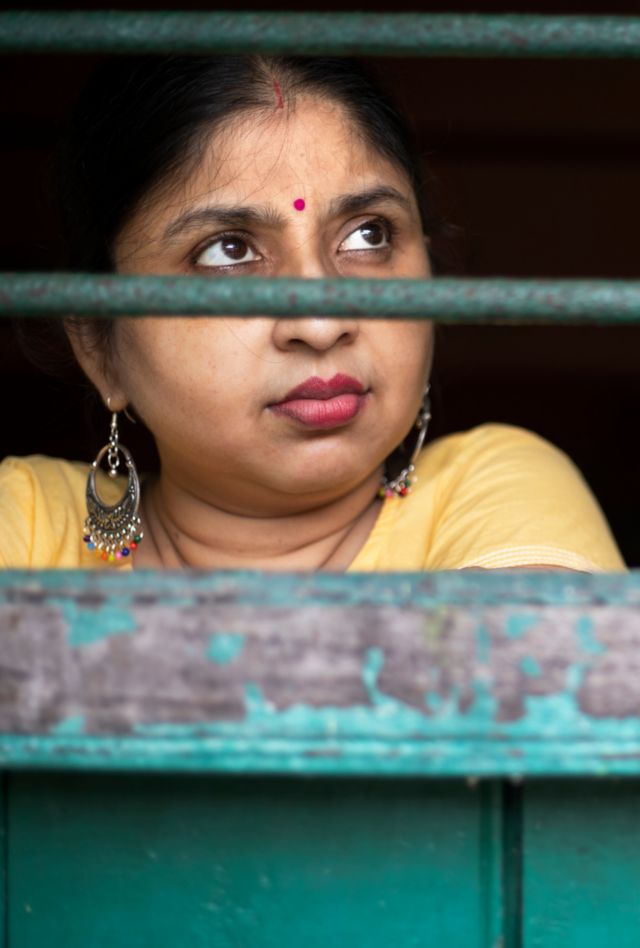 A woman looks out of a barred window