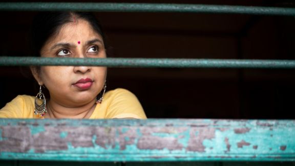 A woman looks out of a barred window