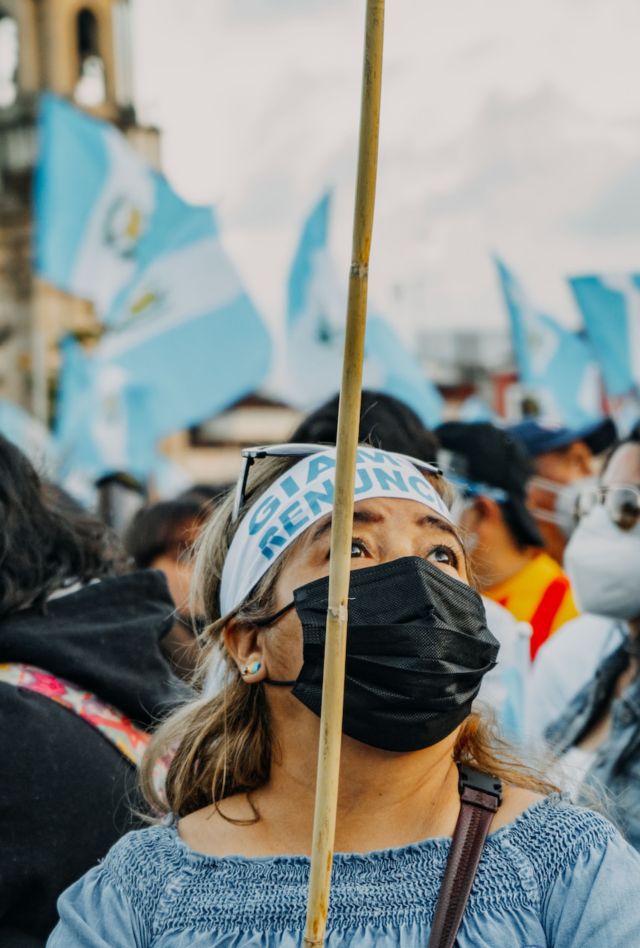 A group of people wearing masks wave Guatemalan flags