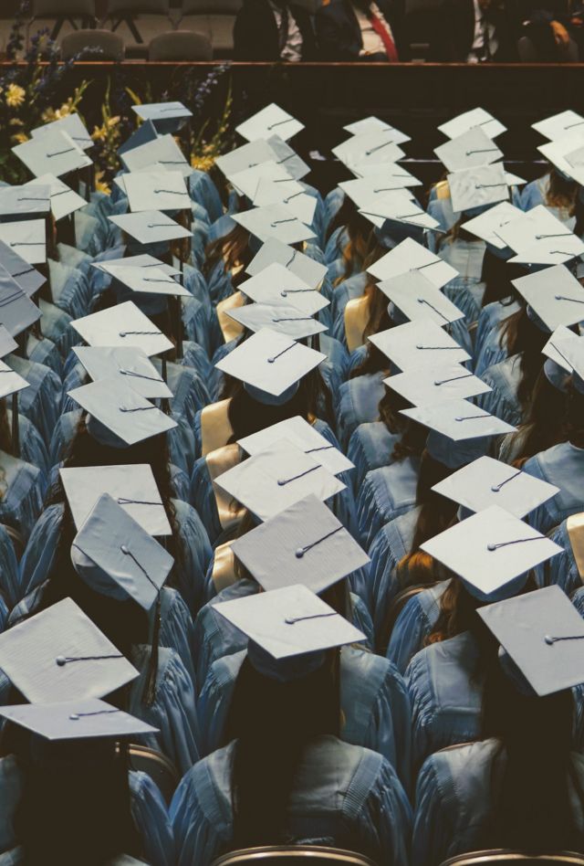 Students seated in rows wear graduation caps and gowns
