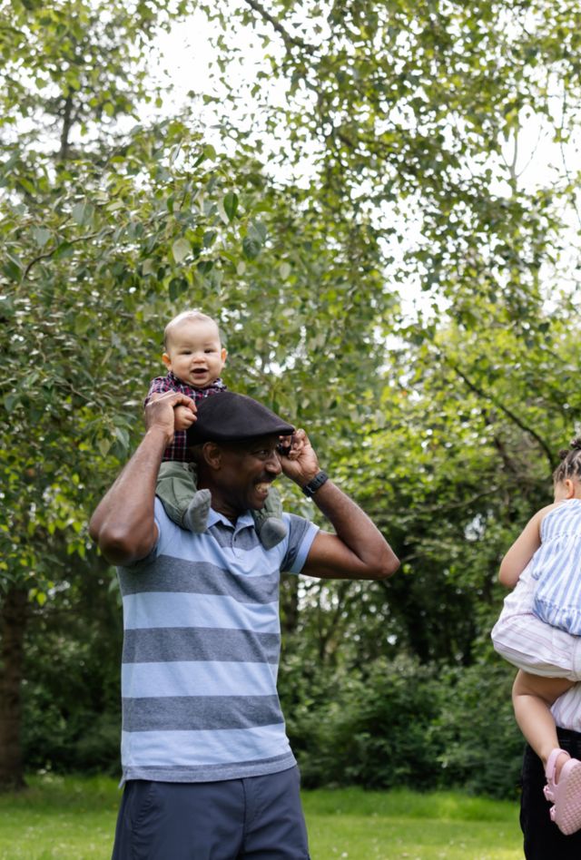 Grandparents enjoying time with grandchildren in the green grass and nature.