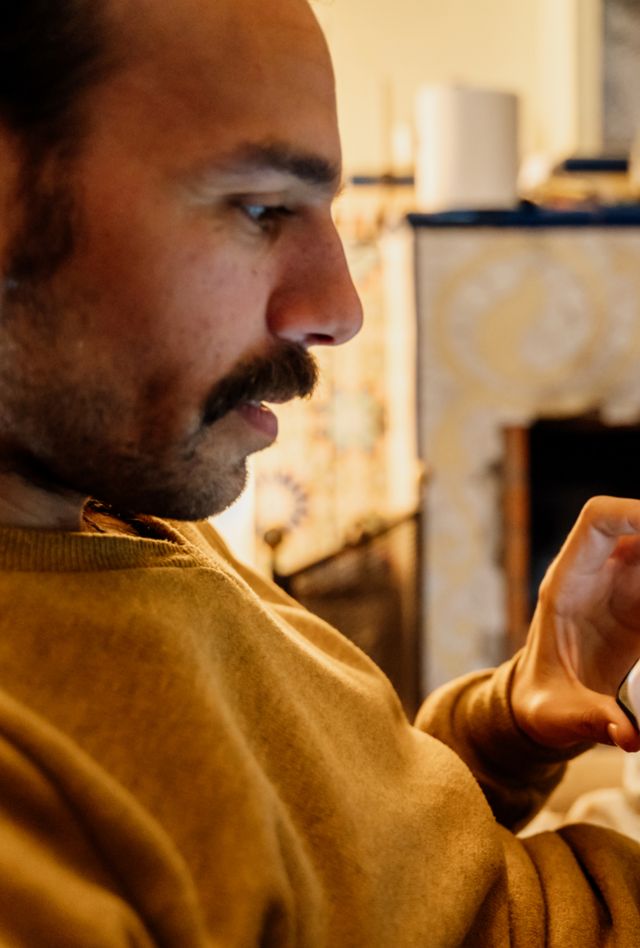 Man using phone posting a photo on social media sitting on couch at home.