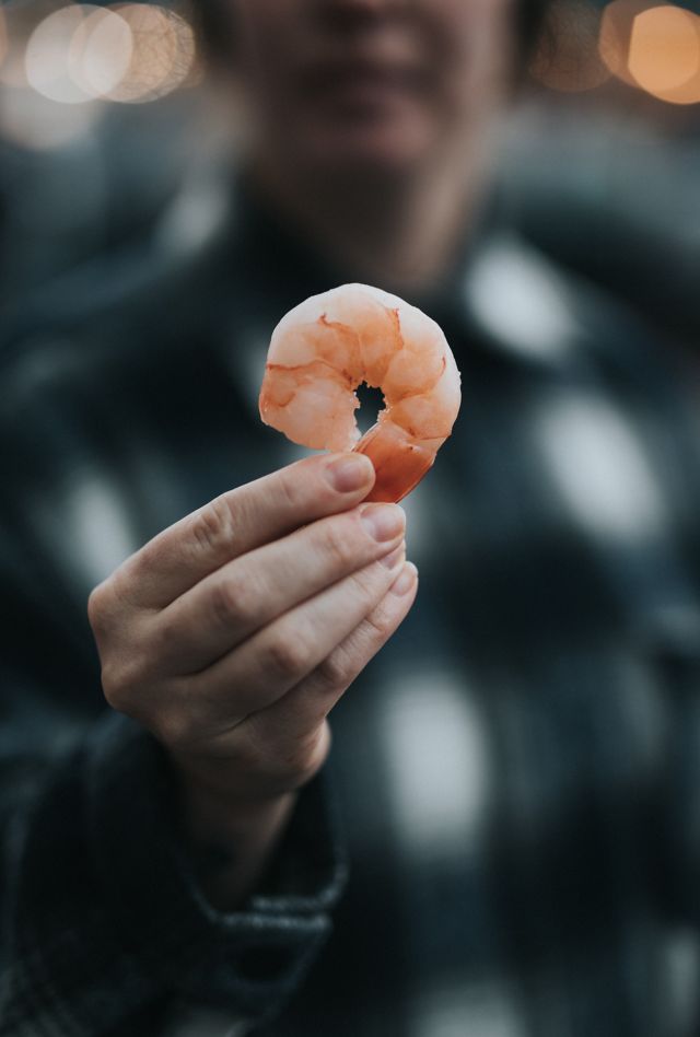 A hand holds up a shrimp