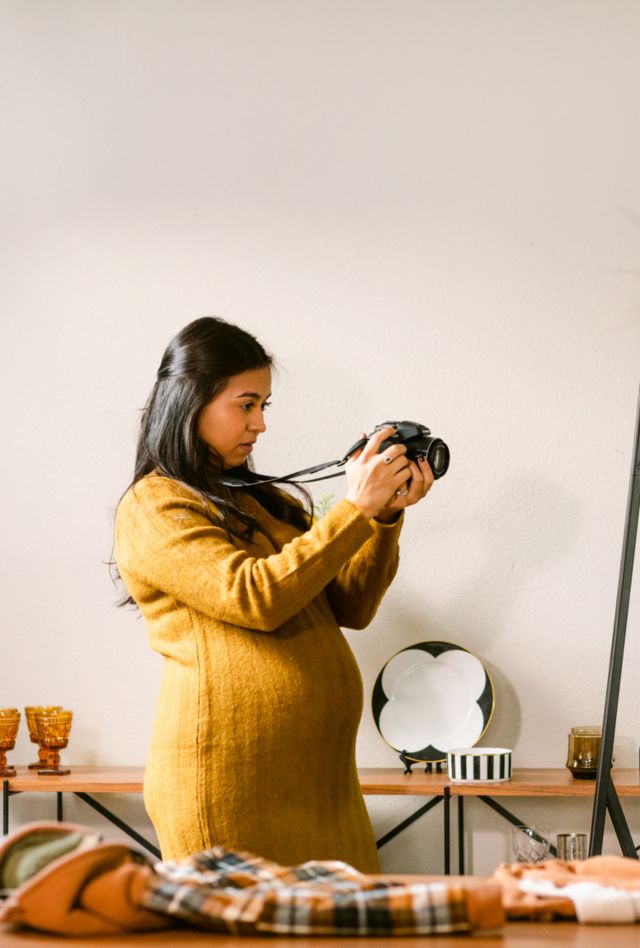 Side view of small business owner taking pictures with professional camera of her products on sale in a clothing boutique
