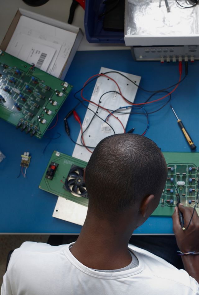 Unrecognizable african-american engineer doing some research work with several electronics circuits and devices on a lab table.