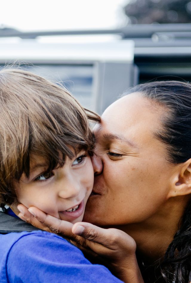 Boy and his mother hug as she drops him off at school