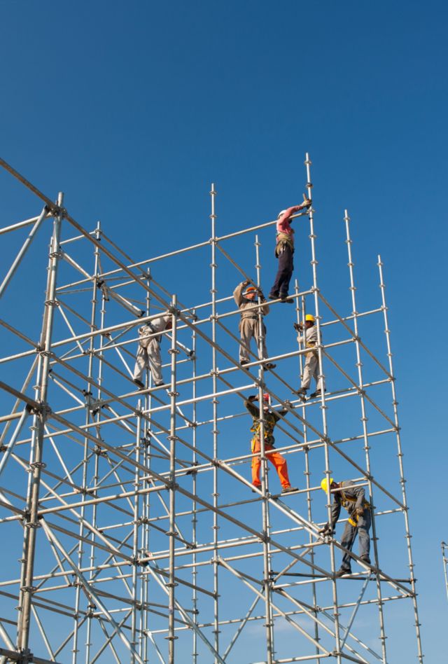 Workers erect metal polls to build a sports stadium event in Riio de Janeiro, Brazil