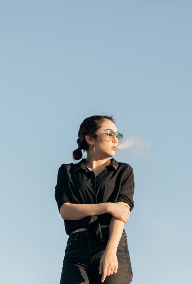 young woman smoking with cloud puff smoke in front of face