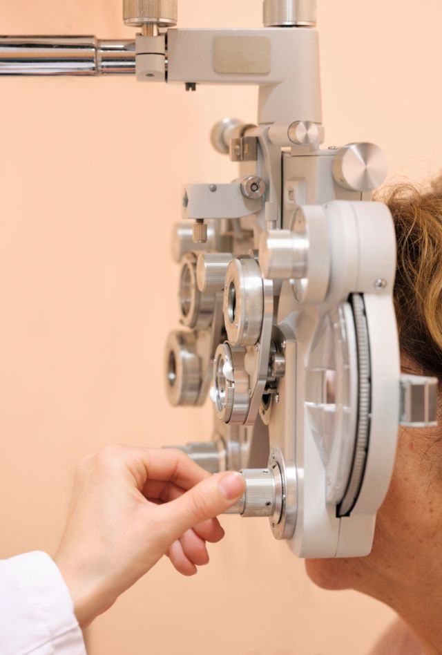 Anonymous adult woman patient is having an eyesight test by optician with optometrist equipment