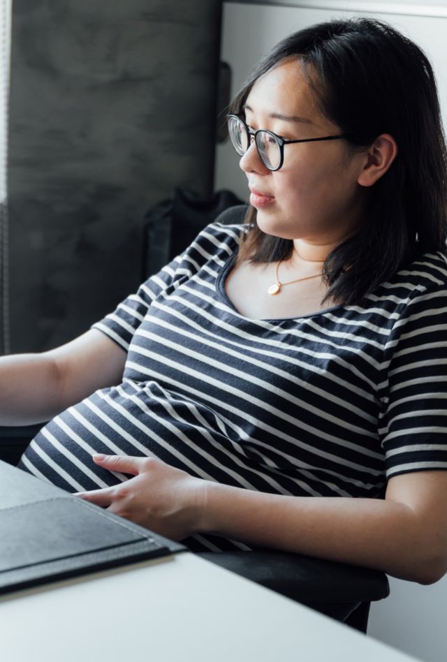Young pregnant woman working in office with computer