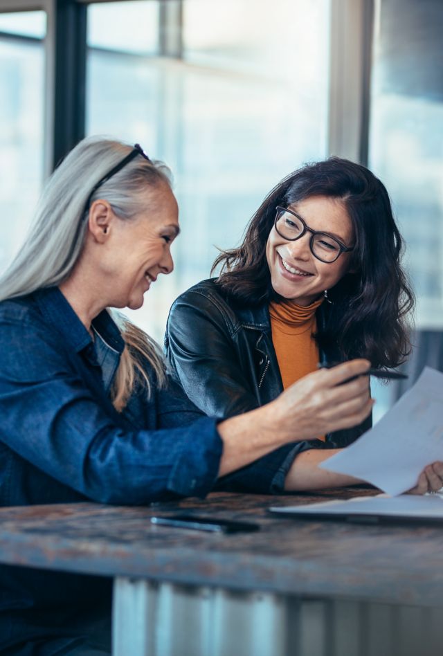 Smiling business woman working together on contract documents. Happy coworkers meeting for new project planning in office.