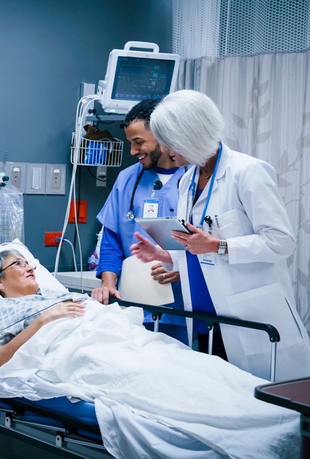 Doctor and nurse talking with patient in hospital bed