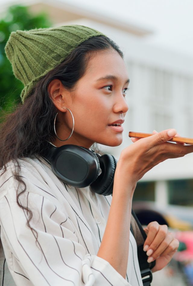 Young asian woman standing on the street talking into a pink cell phone