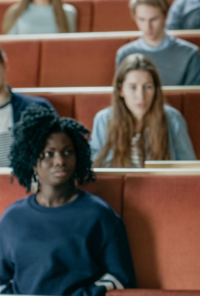 A professor addresses a lecture hall of students. He's holding a laptop that is open to a screen titled "Deep Learning."