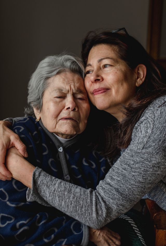 Portrait of woman in wheelchair hugging daughter with positive face. Third old age, Home care concept.