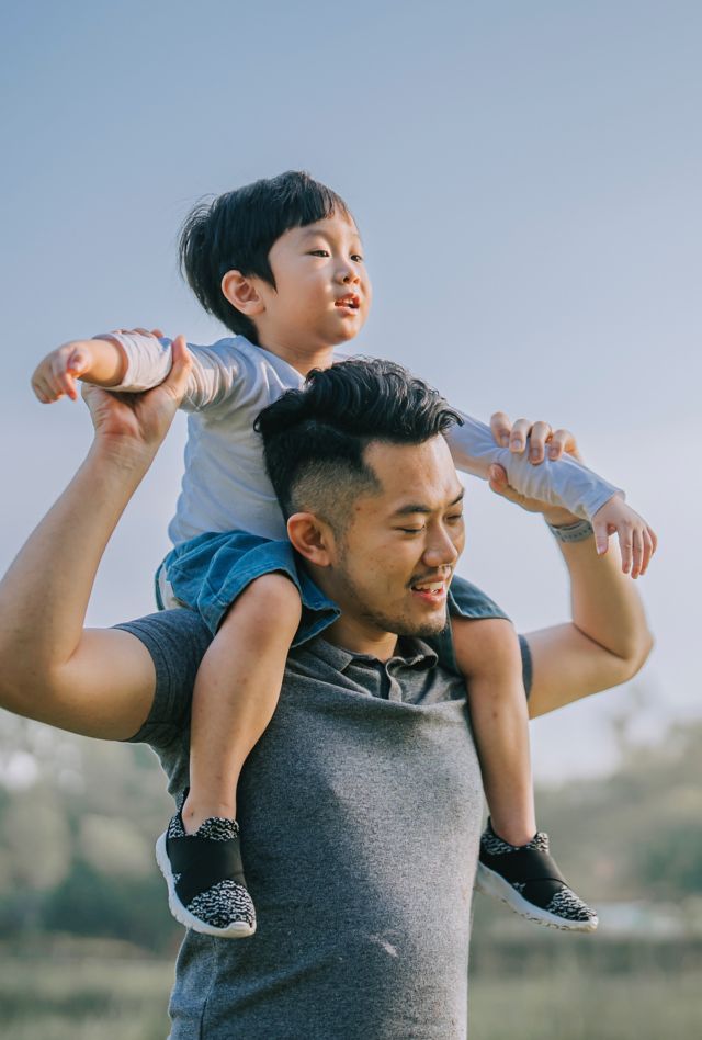 Asian American male carrying an Asian American toddler on his shoulders