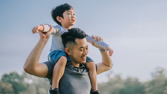 AAPI adult male carrying a toddler on his shoulders