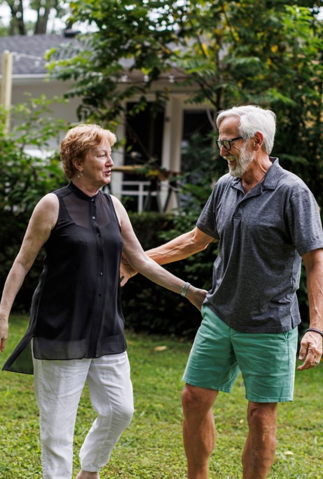 An older woman and man standing on a lawn and looking at each other