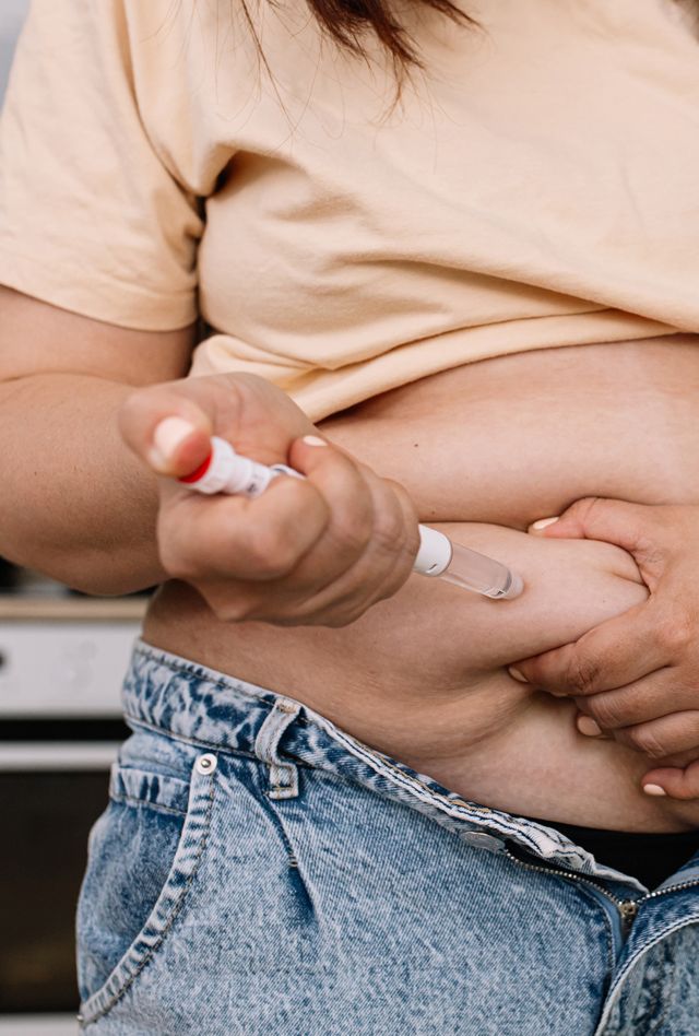 Injections for weight loss with Semaglutide. An obese woman gives a hormone glucagon-like peptide-1 (GLP-1) injection into the abdomen with a pen syringe.