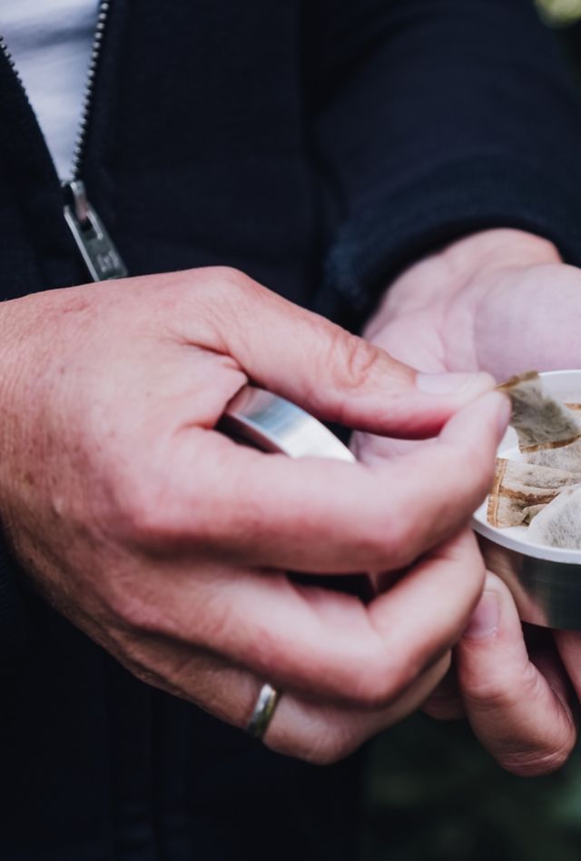 Hands holding a tin of smokeless tobacco