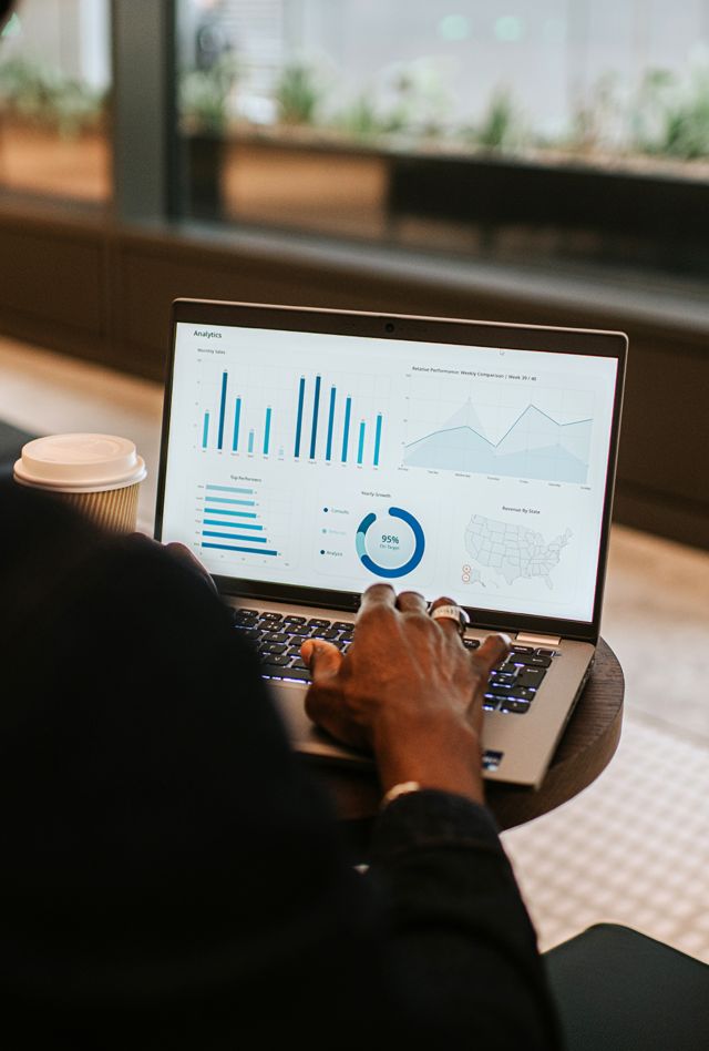 Focus on a laptop screen. A man uses a laptop and looks at financial figures, including graphs and charts.