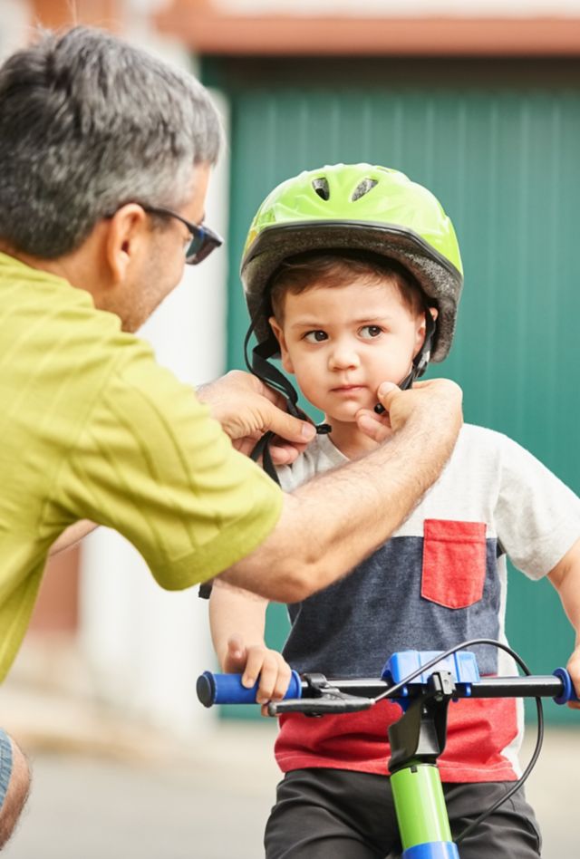 Shot of a father helping son wearing helmet for cycling outdoors