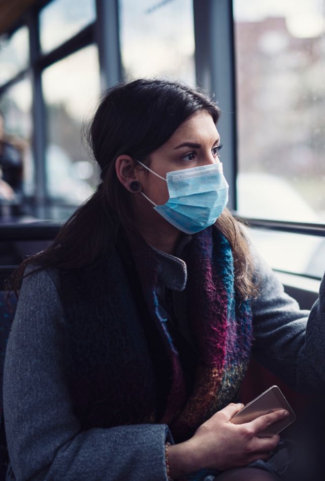 Young woman wearing protective face mask, she sitting in bus transportation in the city.