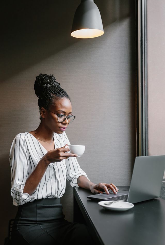 Woman holding a mug while reading laptop