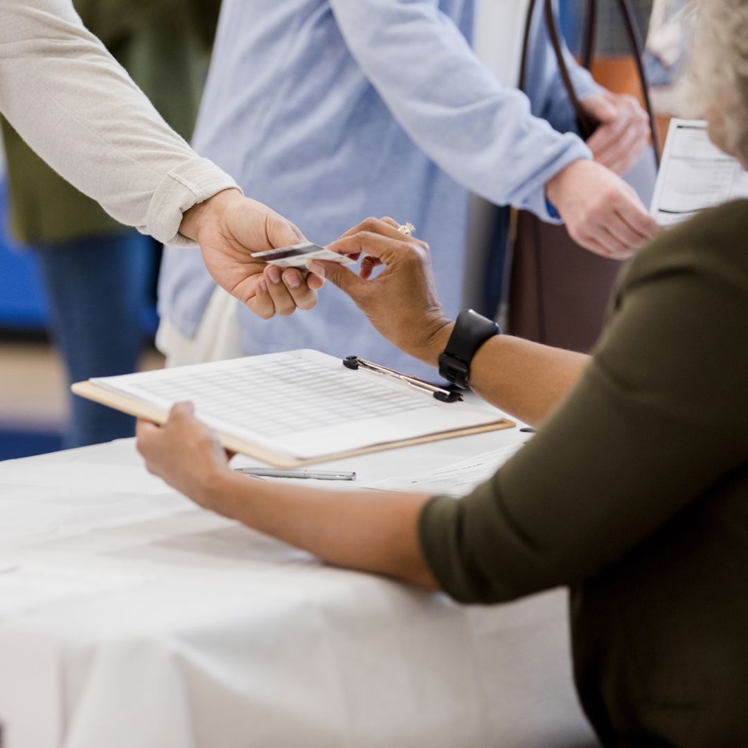 person giving their ID to a polling place volunteer
