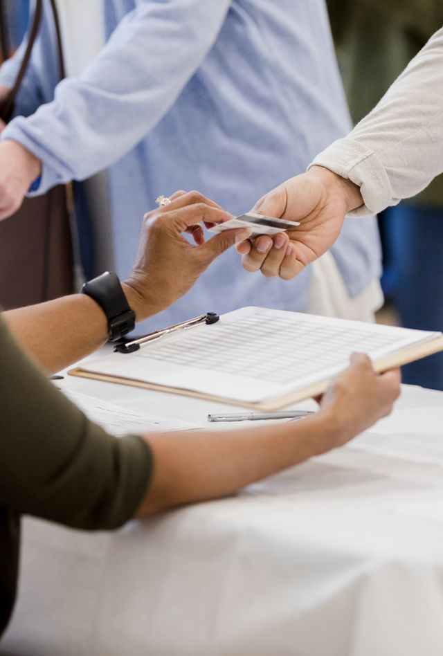 person gives his ID to a polling place volunteer