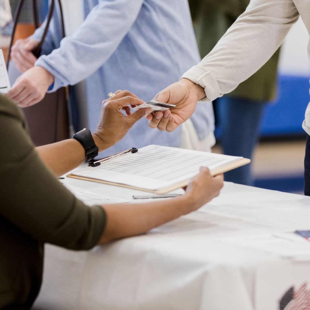 person giving their ID to a polling place volunteer