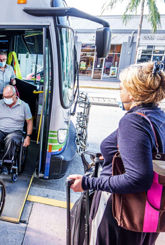 2HCJJ3M Miami Beach Florida bus stop Miami-Dade Metrobus disabled handicapped woman man couple getting off wheelchair wheelchairs wearing face mask masks Covi