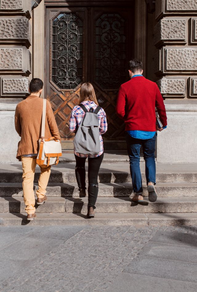 Group of college students entering the university building together.